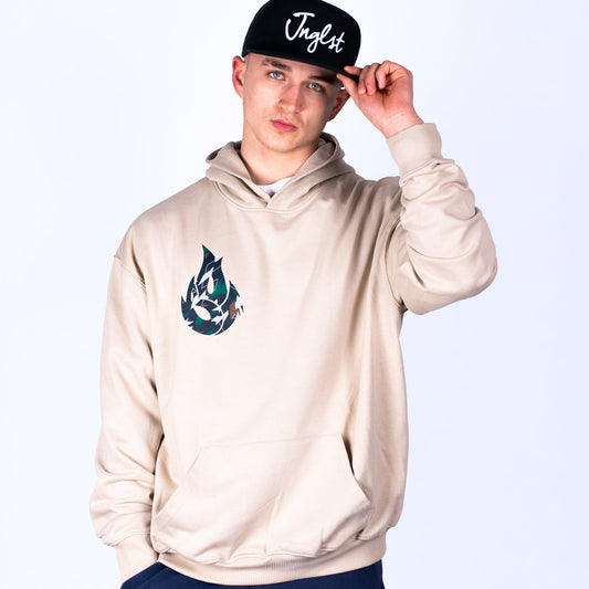 Person wearing a beige hoodie with a logo and a black cap with text on a white background