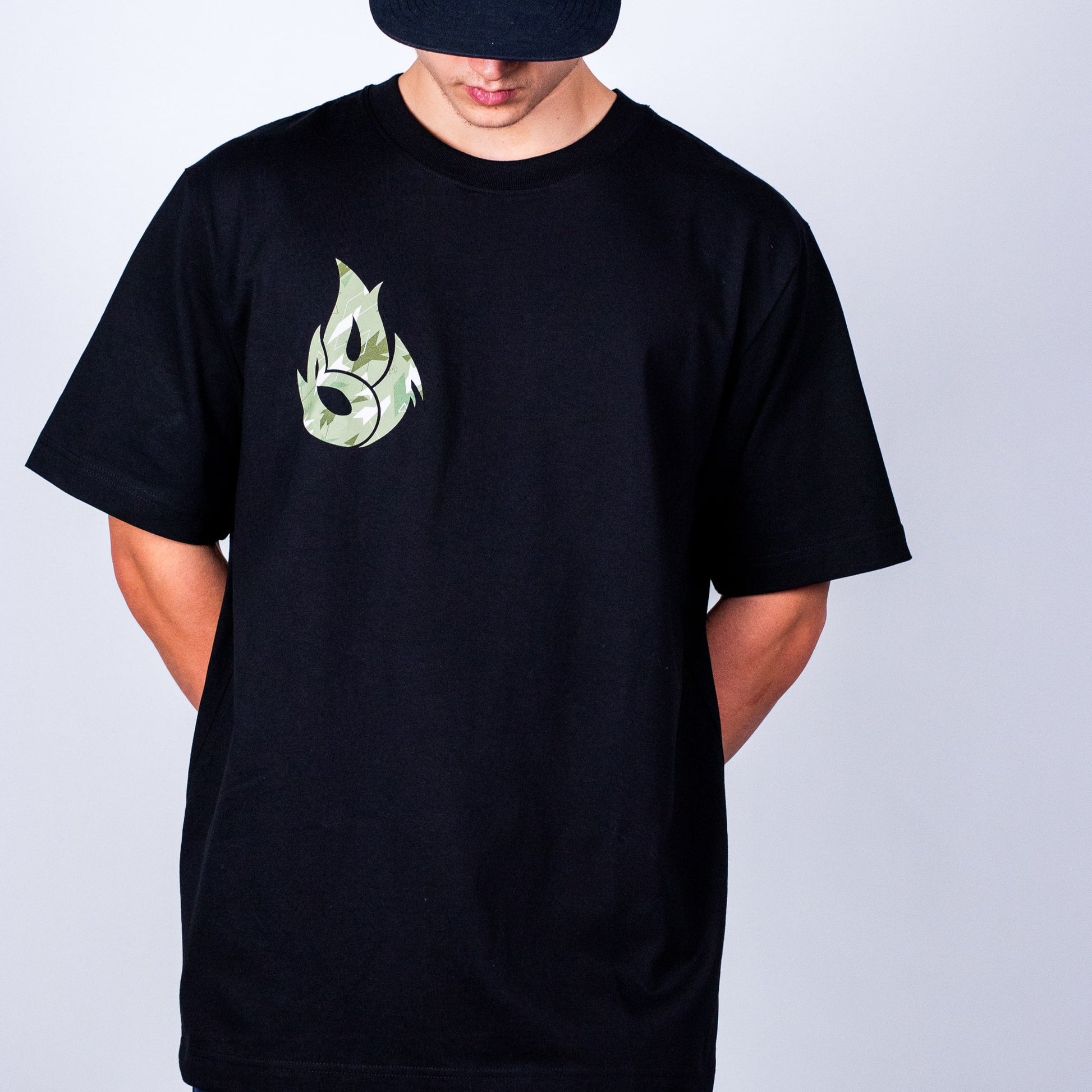 Person wearing a black t-shirt with a green logo on a plain background