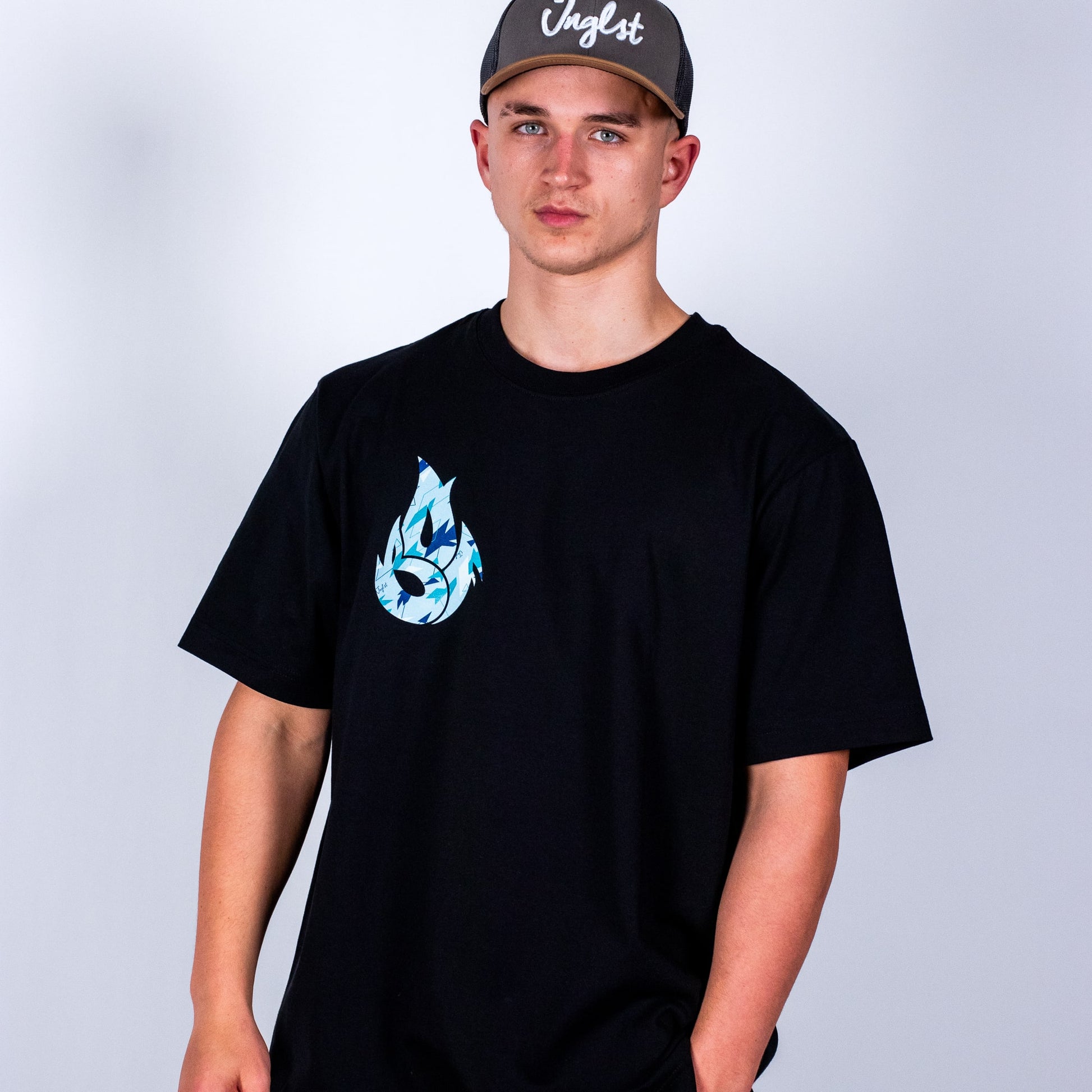 Person wearing a black t-shirt with a blue camo graphic design and a cap on a light grey background