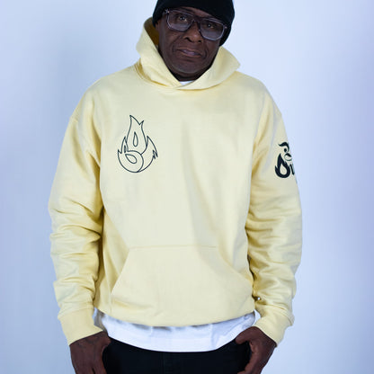 Person wearing a light yellow hoodie with black designs on a plain background