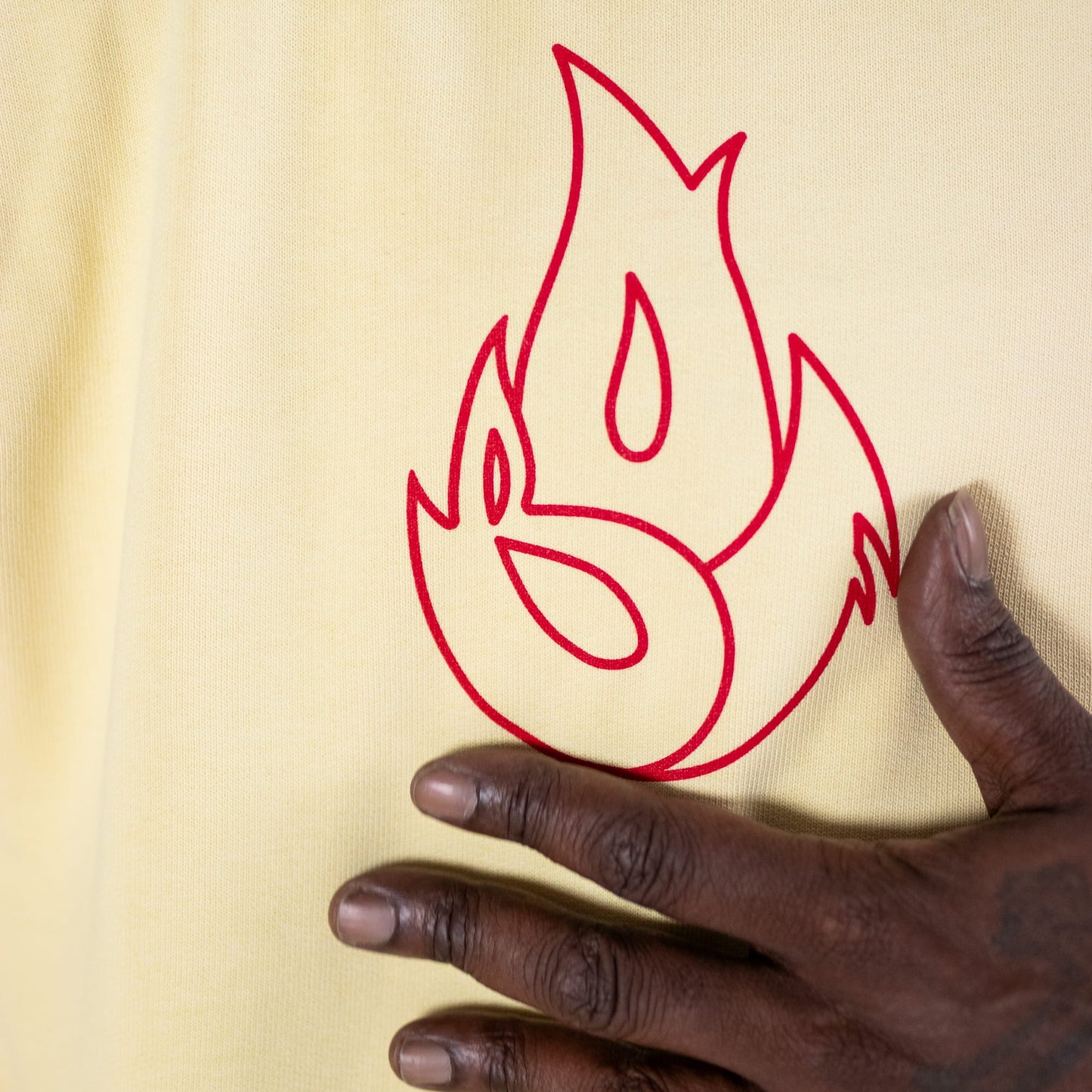 Hand touching a red flame design on a yellow background