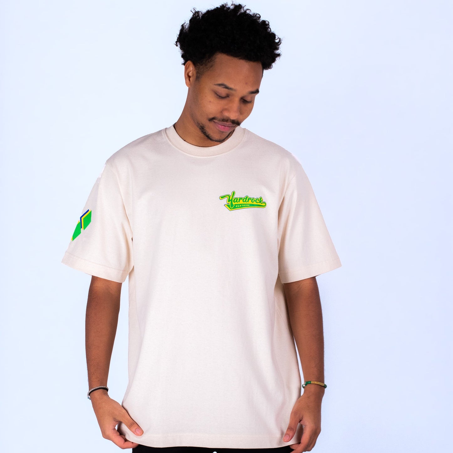 Man wearing a white yardrock t-shirt with logos on a light blue background