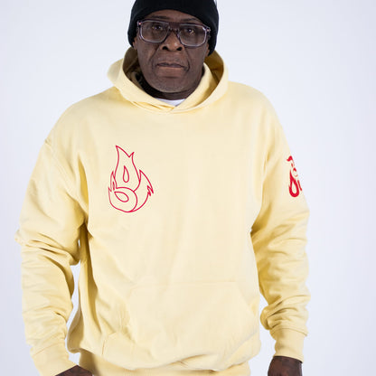 Man wearing a light yellow hoodie with red designs on a white background