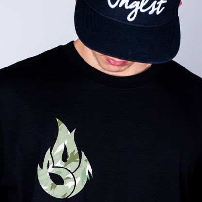 Person wearing a black t-shirt with a green logo and a dark cap with white text.