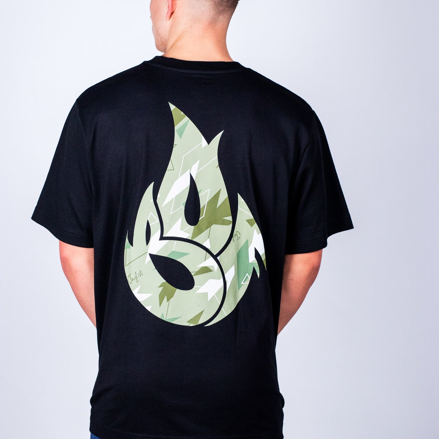 Person wearing a black Born Outta Fire t-shirt with a green camo flame design on the back against a plain background
