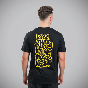 A man viewed from behind wearing a black t-shirt with a large yellow graphic text on the back reading 'PLAY THAT BLOODY JUNGLE MUSIC NIGHT'.