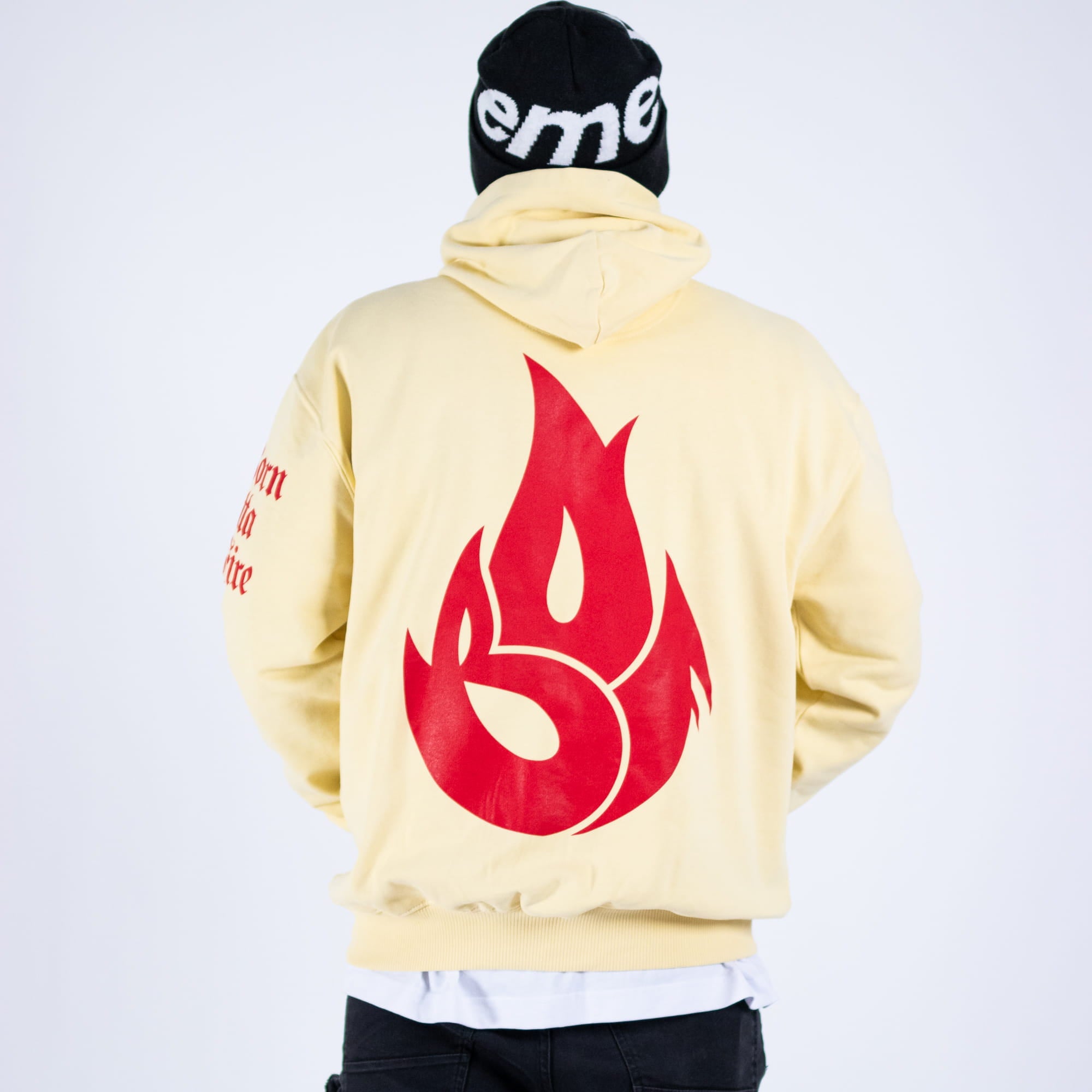 Person wearing a light-colored hoodie with a red flame design on the back, standing against a white background.