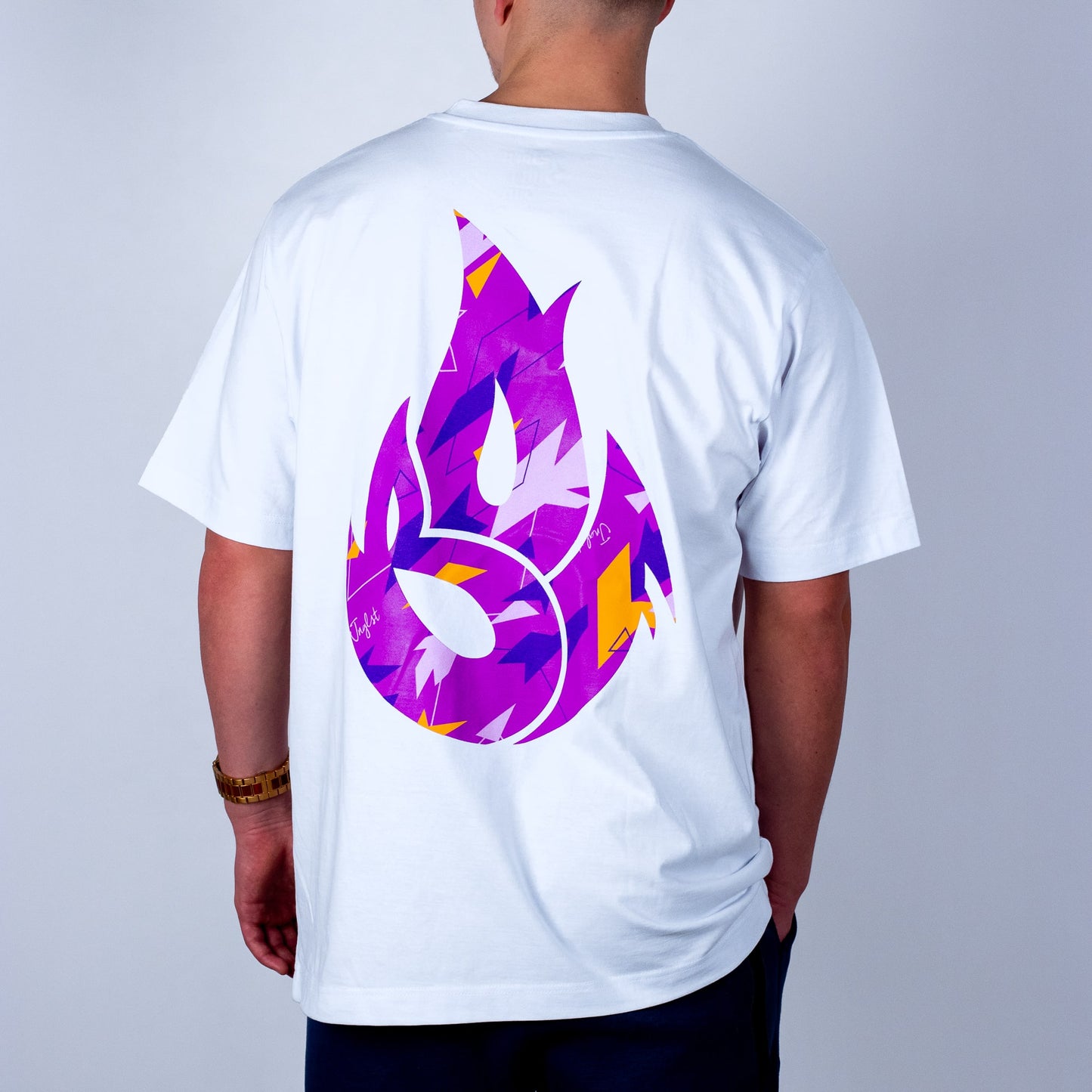 Person wearing a white t-shirt with a colorful flame logo on the back against a plain background