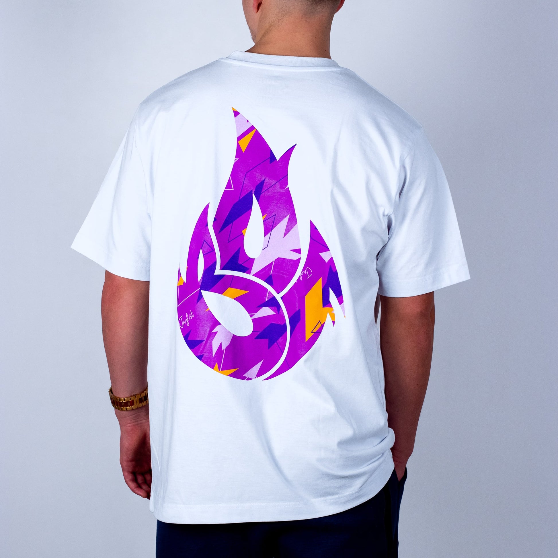 Person wearing a white t-shirt with a colorful flame logo on the back against a plain background