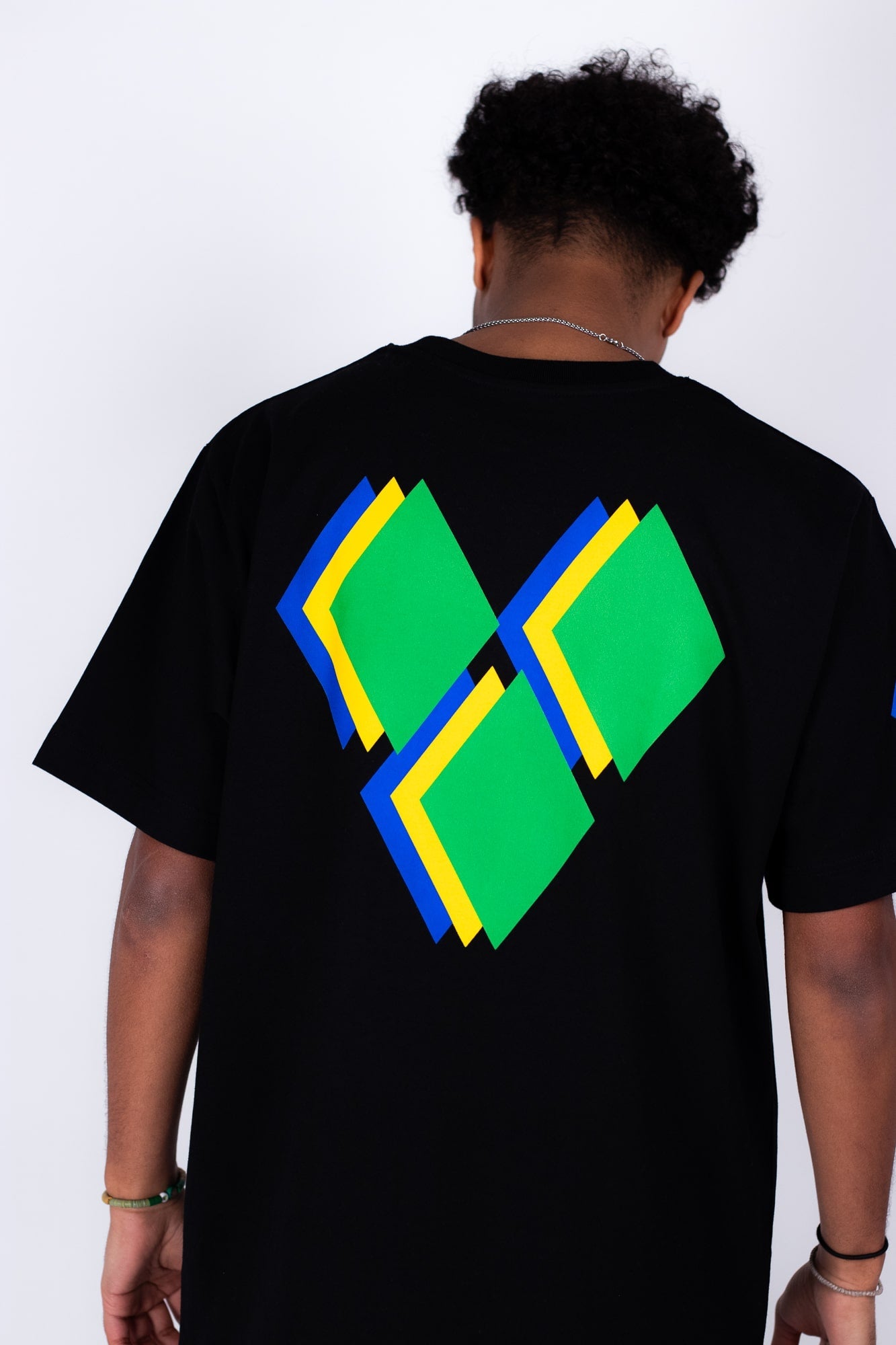 Person wearing a black t-shirt with colorful geometric design on the back against a white background