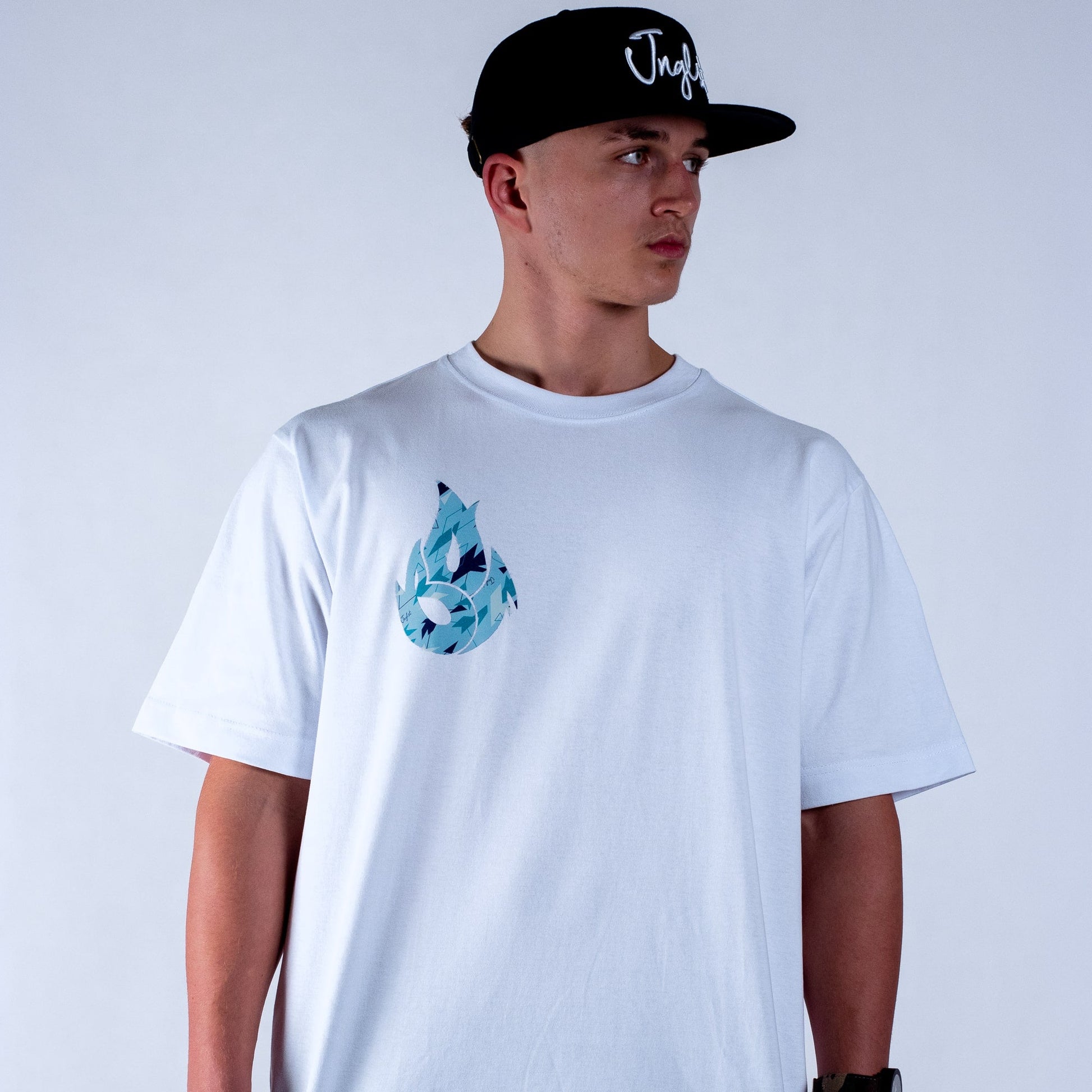 Person wearing a white Junglist t-shirt with a blue graphic design and a black cap on a light grey background